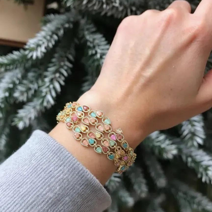 Hand wearing a colorful bracelet with a blurred green background
