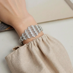 Silver bracelet on a wrist with a neutral background