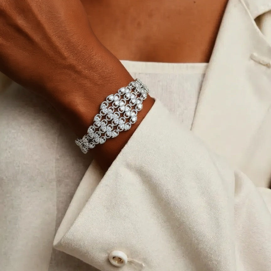 Silver bracelet on a wrist with a beige coat background