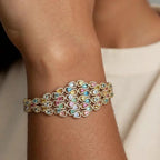 Multicolored gemstone bracelet on a wrist with a neutral background